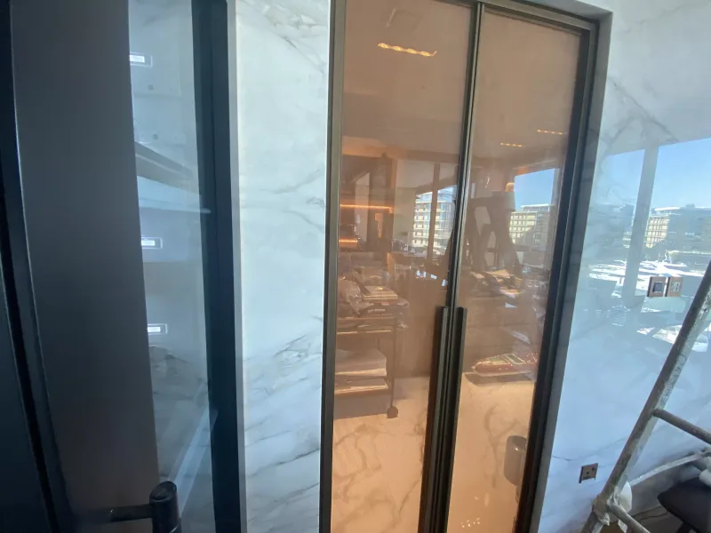 Bronze-framed tinted glass double doors with black pull handles in a marble interior