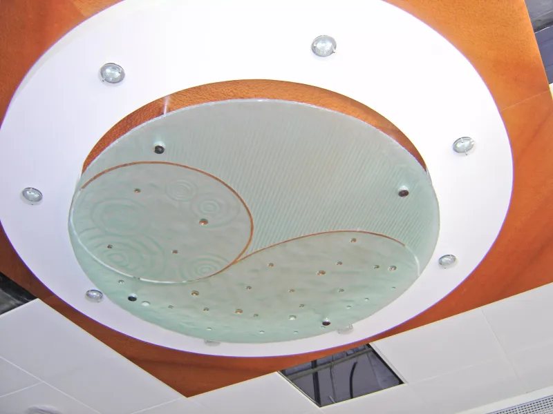 Circular relief glass ceiling feature with swirl pattern inside a timber and white ceiling ring