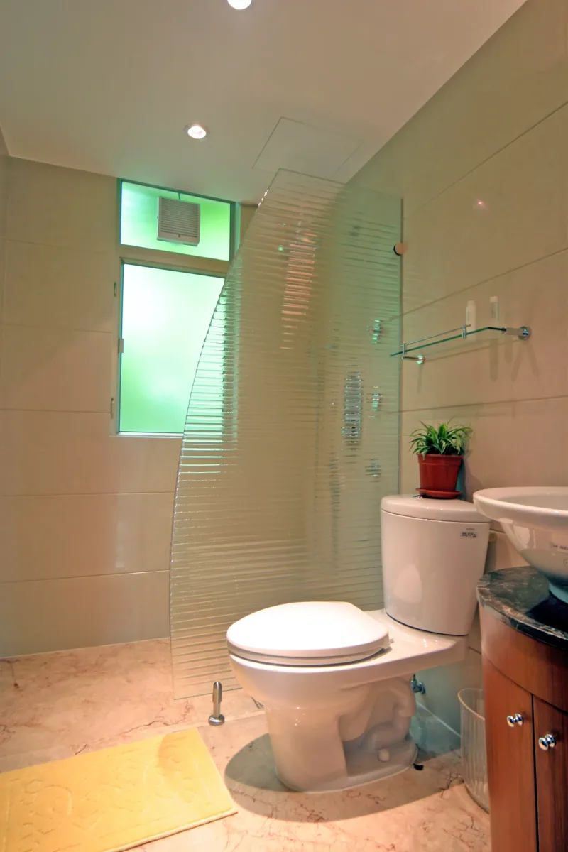 Shaped reeded glass shower partition with curved edge in a compact bathroom
