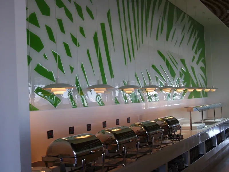 White glass wall with green palm leaf pattern behind a restaurant buffet counter