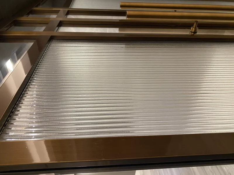 Close-up of reeded glass panel in a polished bronze door frame with brass handles