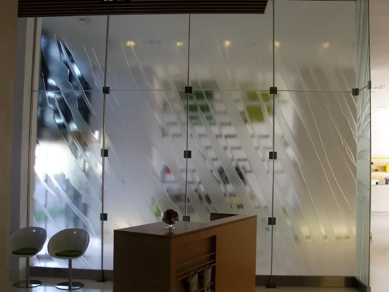 Textured relief glass partition behind a reception desk with stainless steel posts and fittings