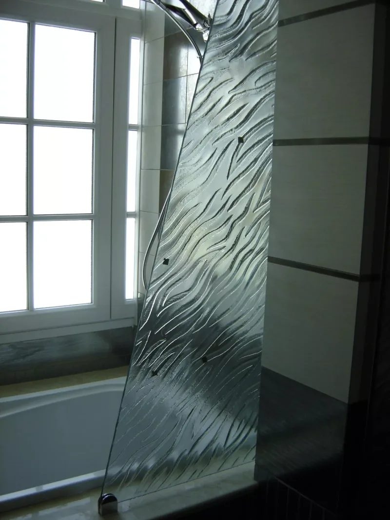 Tapered textured glass bath screen with wave relief pattern beside a window and bathtub