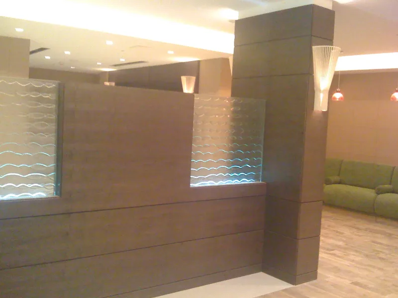 Backlit wave-pattern glass inserts in a timber-panelled lobby partition