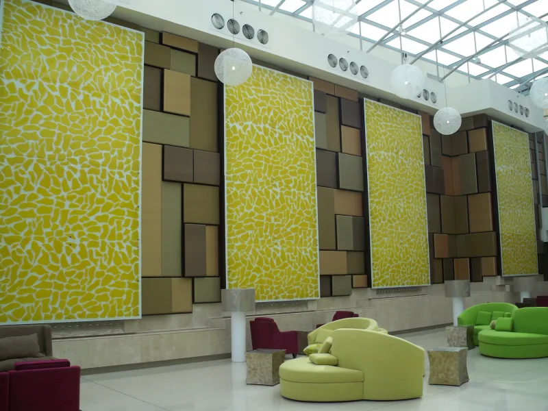Large yellow decorative cast glass wall panels in an atrium lobby with skylight